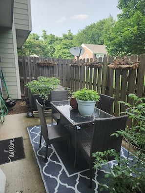 Eine Terrasse mit Tisch und Stühlen, umgeben von einem Holzzaun und Blumentöpfen.