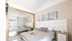 Un dormitorio con cama, mesita de noche, espejo y cuadros en la pared.