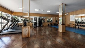 Un gimnasio con cintas de correr, máquinas de pesas y un suelo acolchado azul.