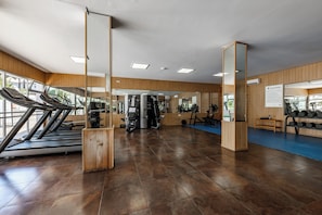 Ein Fitnessstudio mit Laufbändern, Kraftgeräten und einem blauen gepolsterten Boden.
