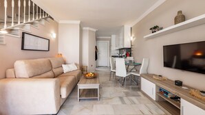 Una sala de estar moderna con sofá, mesa de centro, televisor y una escalera.