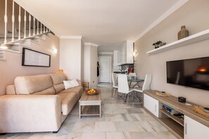 Ein modernes Wohnzimmer mit einer Couch, einem Couchtisch, einem Fernseher und einer Treppe.