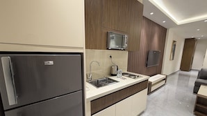 A modern kitchen with a built-in microwave, a stainless steel refrigerator, a sink with a faucet, and a countertop with a toaster and water bottles. - 003jre Apartment With Stunning Boulevar (Amman)