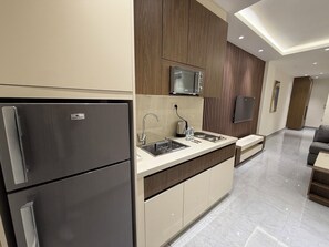 Eine moderne Küche mit Einbau-Mikrowelle, einem Edelstahl-Kühlschrank, einer Spüle mit Armatur und einer Arbeitsplatte mit Toaster und Wasserflaschen.