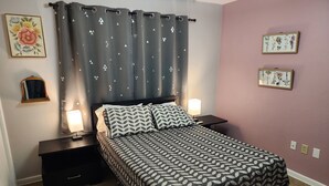 Een slaapkamer met een bed, twee nachtkastjes, een spiegel en een muur met twee ingelijste foto's.
