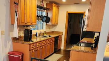 Cocina compacta con armarios de madera, cafetera y lavamanos.