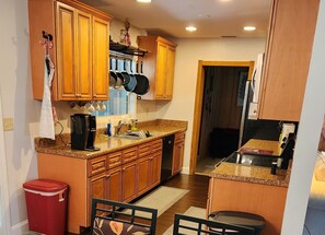 Cocina compacta con armarios de madera, cafetera y lavamanos.