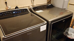Twee Whirlpool wasmachines in een wasserij, met een boiler en een afvalbak.