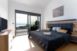 Ein Schlafzimmer mit einem Bett, einem Fernseher, einer Schiebetür und einem Bild an der Wand.