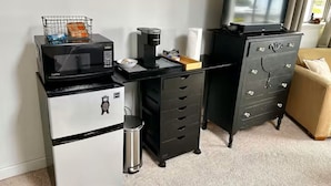Eine Küchenzeile mit Mikrowelle, Kaffeemaschine und einem kleinen Mülleimer.