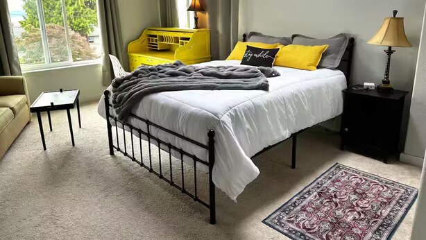 Ein Schlafzimmer mit einem Bett, Nachttischen, einem Fenster und Blick ins Grüne.