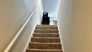 Eine Teppichstufen-Treppe mit weißen Wänden und einer Deckenleuchte.