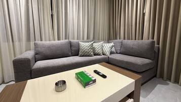 A modern living room with a grey sectional sofa, a wooden coffee table, and a remote control.