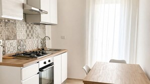 A modern kitchen with white cabinets, a wooden countertop, and a dining table with chairs. - Room with private bathroom in apartment near policlinico cittadella catania (Gravina di Catania)