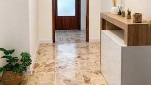 A hallway with a stone floor, a wooden door, and a reception desk with plants. - Room with private bathroom in apartment near policlinico cittadella catania (Gravina di Catania)