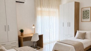 A bedroom with two beds, a desk, a chair, and a ceiling light fixture. - Room with private bathroom in apartment near policlinico cittadella catania (Gravina di Catania)
