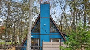 Een chalet met een puntig dak, grote ramen en een blauwe buitenkant.