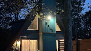 Een modern huis met een opvallende verticale constructie, een veranda en een omheinde tuin.