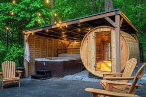 Eine Holzhütte mit Whirlpool, zwei Adirondack-Stühlen und Lichterkette.