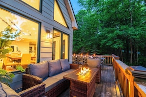A deck with a fire pit, outdoor seating, and a view of a forested area. - Wintergreen 5BR w/ Hot Tub, Sauna. Walk to slopes! (Wintergreen Resort)