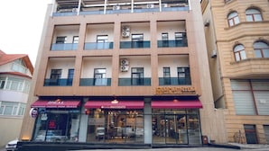 Un hôtel à plusieurs étages doté d’une façade moderne, de climatiseurs et d’un café situé au rez-de-chaussée.