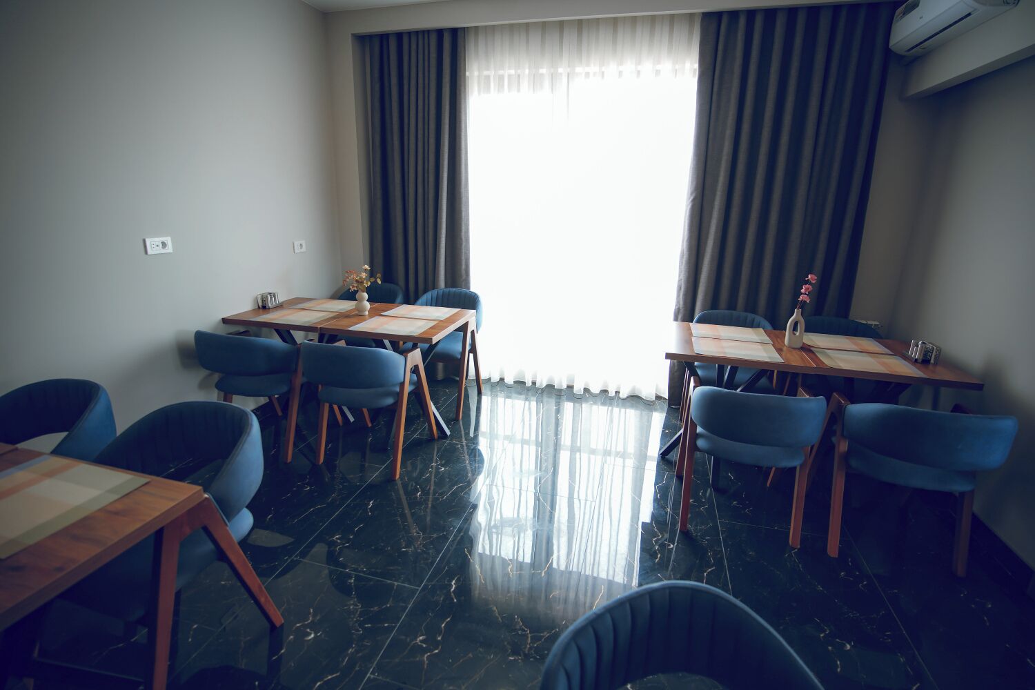 Un salón de conferencias con una gran mesa y sillas, una ventana con cortinas y un piso de mármol.