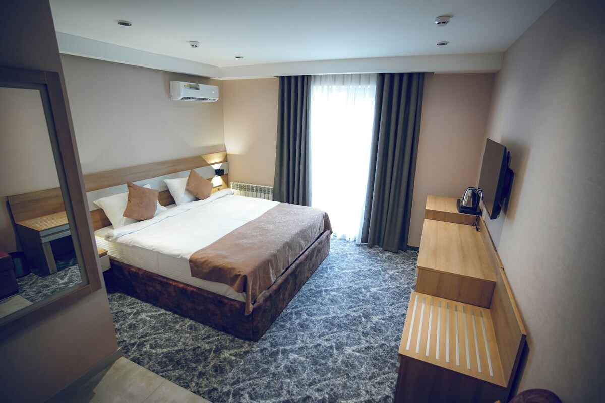Een hotelkamer met een groot bed, een bureau, een spiegel en een televisie.