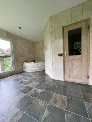 Ein Badezimmer mit einer Badewanne, einer Holztür und Fliesenböden.
