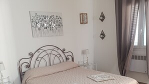 Ein Bett mit gesteppter Bettdecke, ein Nachttisch mit Lampe und Wanddekoration.