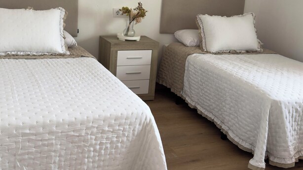 A bedroom with two beds, a nightstand, and decorative wall art.