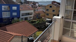 A balcony with a metal railing, a view of a residential area with various buildings, and a clear sky.