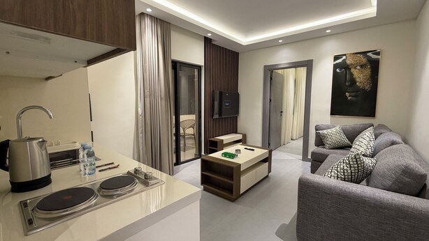 A modern living room with a sofa, a coffee table, and a television. - 005 JRE Apartment With Stunning Boulevard Veiw (Amman)