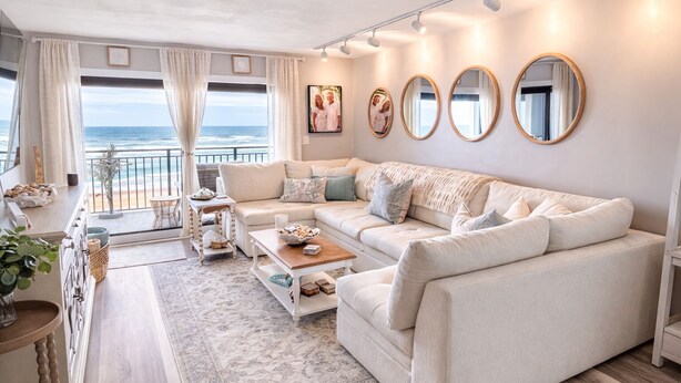Een woonkamer met een bank, salontafel en uitzicht op de oceaan.