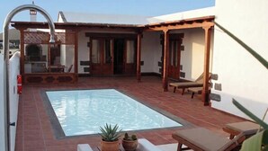Ein Pool auf dem Dach mit einer Pergola, Liegestühlen und Topfpflanzen.