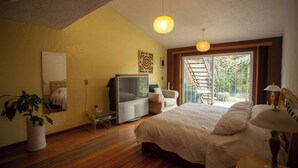 A bedroom with a bed, bedside table, lamp, potted plant, and a sliding door leading to a balcony. - House with garden in front of the Pyramid of Cholula, Puebla,MX (PUEBLA)