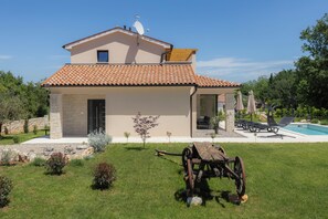 A modern two-story house with a swimming pool, outdoor seating, and a stone pathway.
