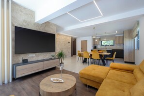 Ein modernes Wohnzimmer mit Flachbildfernseher, Essbereich und Küche.