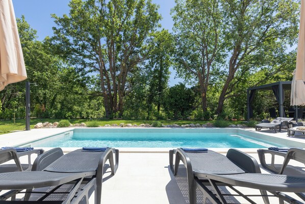 A swimming pool with lounge chairs and a pergola.