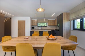 A modern kitchen with a wooden table, yellow chairs, and a fruit bowl.
