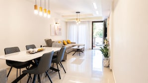 A modern living room with a dining table, sofas, and a large window. - Fems Luxury 3-level Home w Private Jacuzzi (Heraklion)