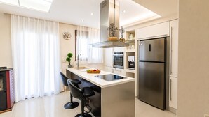 A modern kitchen with a central island, stainless steel appliances, and a dining area with bar stools. - Fems Luxury 3-level Home w Private Jacuzzi (Heraklion)