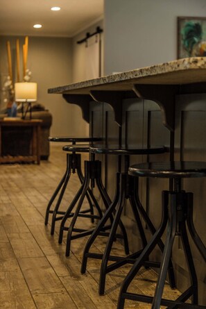 Eine Bar mit Holzboden, Metall-Barhocker und einer Arbeitsplatte.