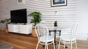 Una sala de estar moderna con televisor de pantalla plana, muebles blancos y una planta en maceta.