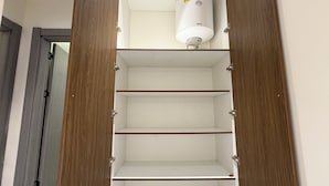 Un placard avec des portes en bois et trois étagères, dont l’une est surmontée d’un objet cylindrique blanc.