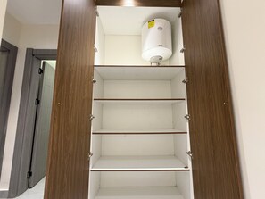 Un placard avec des portes en bois et trois étagères, dont l’une est surmontée d’un objet cylindrique blanc.
