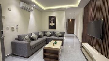Una sala de estar moderna con un sofá modular, una mesa de centro, un televisor de pantalla plana y una pared decorativa de madera.