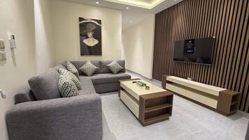 Una sala de estar moderna con un sofá modular, una mesa de centro, un televisor y una pared de acento de madera.