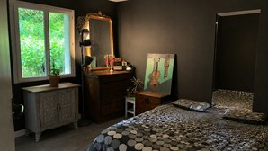 A bedroom with a bed, dresser, vanity, and a window with a view of greenery. - Friendly house surrounded by greenery. (Biriatou)