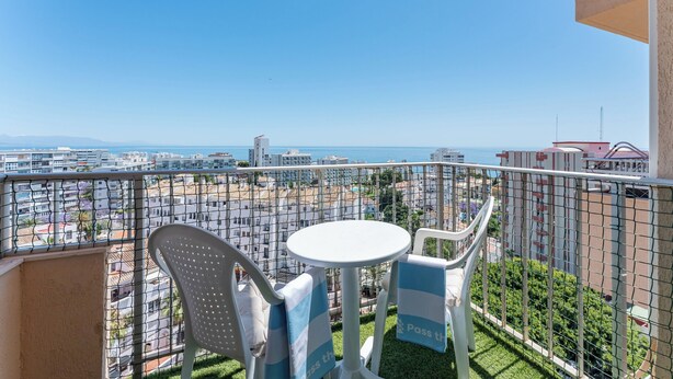 Un balcón con mesa y sillas, que ofrece vistas a la ciudad y al mar.