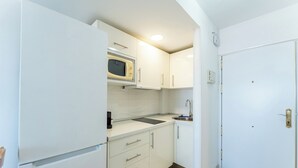 Una cocina compacta con microondas, lavamanos y armarios.